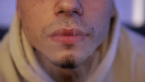 toma de primer plano frontal de un joven fumando de un dispositivo de calentamiento de tabaco en el sofá