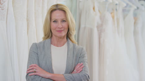 portrait of smiling mature female owner of bridal wedding dress shop