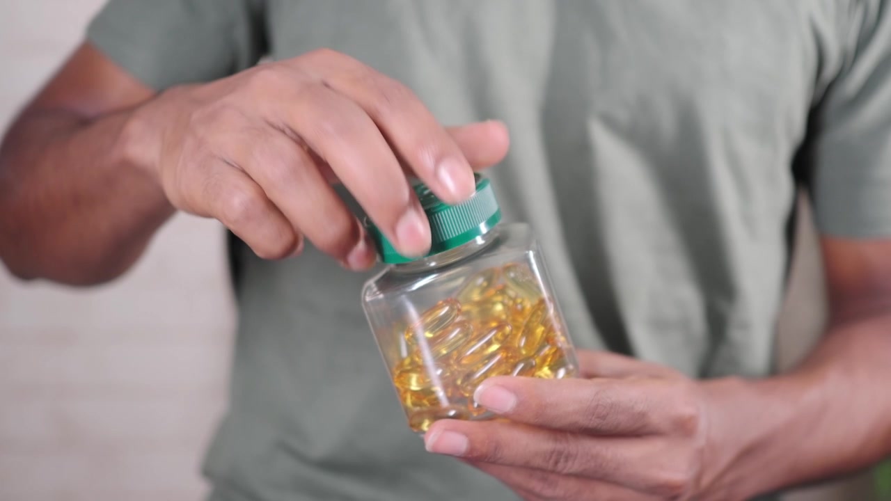 Persona che tiene una bottiglia di capsule di olio di pesce Omega-3.