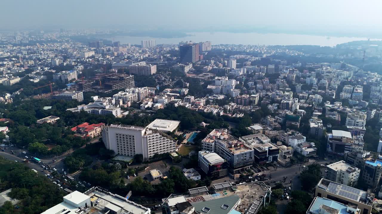 Vista aerea di Hyderabad che mette in risalto un denso sviluppo urbano, edifici di media altezza e spazi verdi con Hussain Sagar visibile sullo sfondo.
