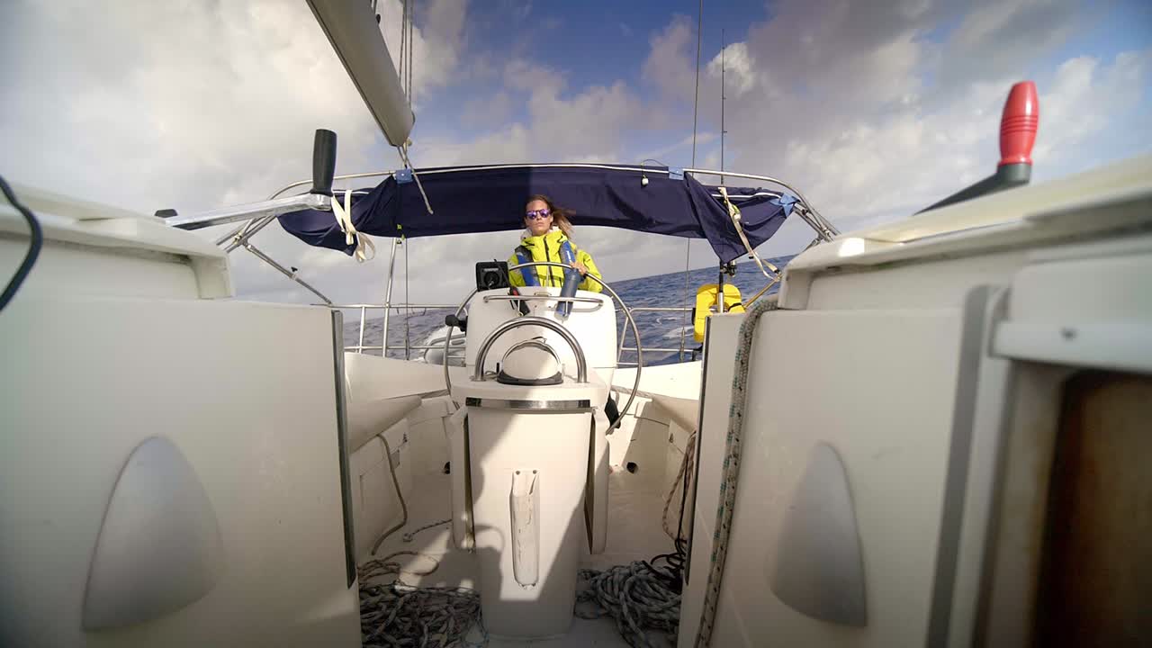 Donna adulta al timone di una barca a vela che naviga da sola in mare aperto, a pieno formato
