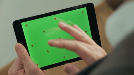 hombre escribiendo con el dedo en la pantalla verde de la tableta. hombre enviando mensajes de texto en la tableta con la tecla chroma