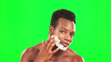 hombre negro, crema de afeitar en la cara y pantalla verde