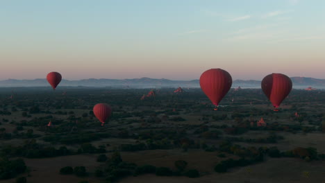 Grupo-De-Globos-Aerostáticos-Sobre-Las-Llanuras-De-Bagan,-Myanmar,-Hermosa-Toma-Aérea-Cinematográfica-De-Gran-Angular