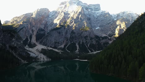 Amanecer-Tranquilo-En-El-Lago-Di-Braies-Con-Fondo-De-Montaña-Iluminado-Por-El-Sol---Revelación-De-Inclinación-Aérea