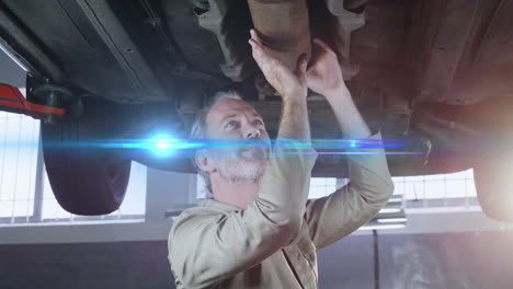 senior mechanic inspecting exhaust pipe on lift in automotive garage, showing lens flare overlay
