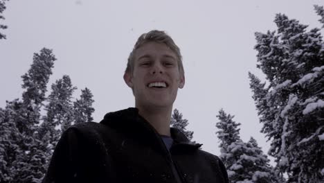 Hiker-Looking-Down-at-Camera-Smiling,-Snowfall-in-Banff-Forest,-4K