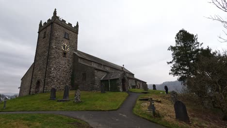 St-Michael-and-All-Angels-Church-in-Hawkshead,-showing-fields-and-grazing-sheep-Cumbria,-UK