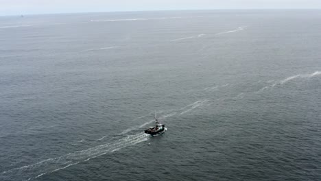 Drone-aerial-of-a-solitary-fishing-boat-traveling-out-to-see-alone-on-a-cloudy-day