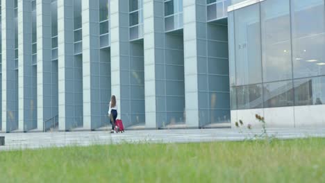 Corporate-woman-with-red-trolley-walking,-hesitates,-then-strides-on