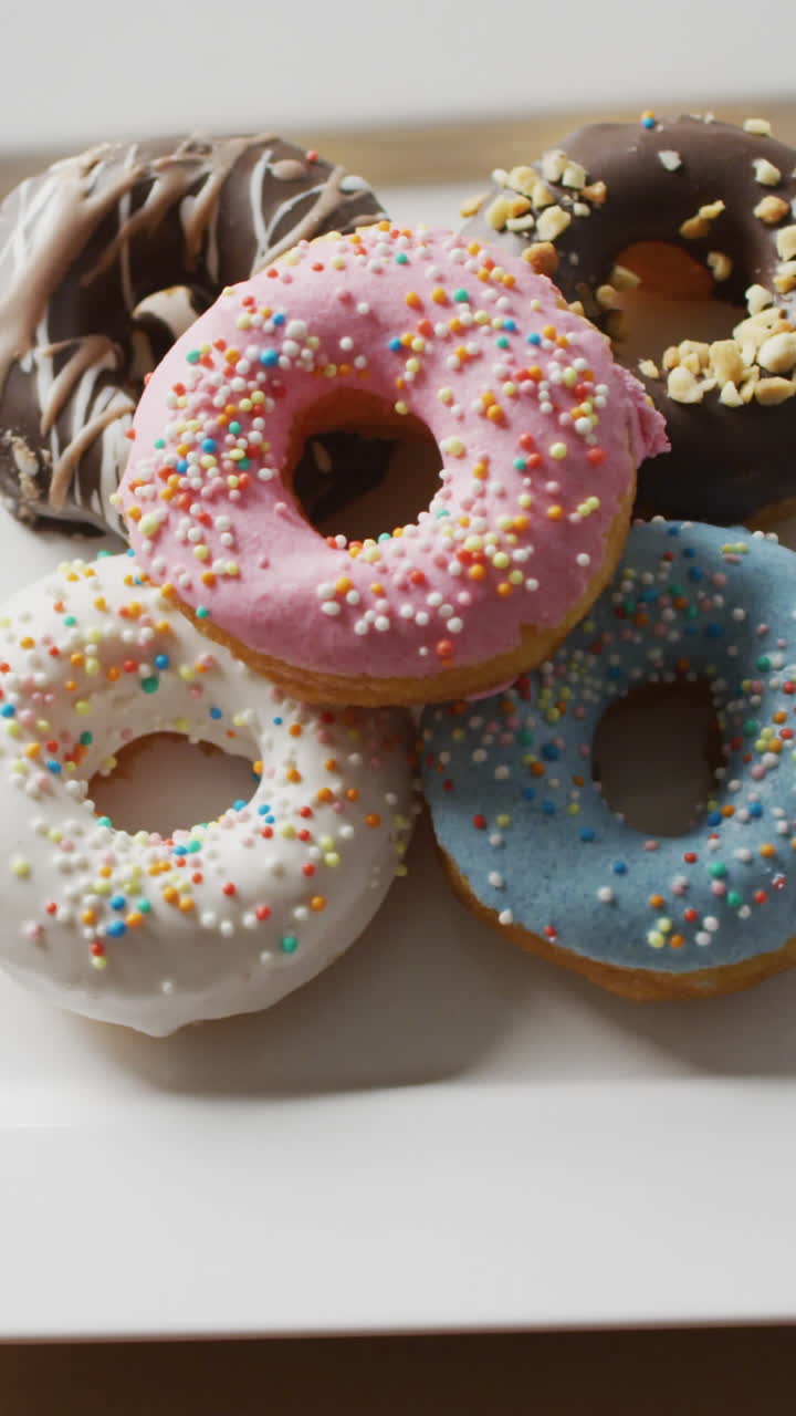 video de rosquillas con glaseado en una placa blanca sobre un fondo rosa