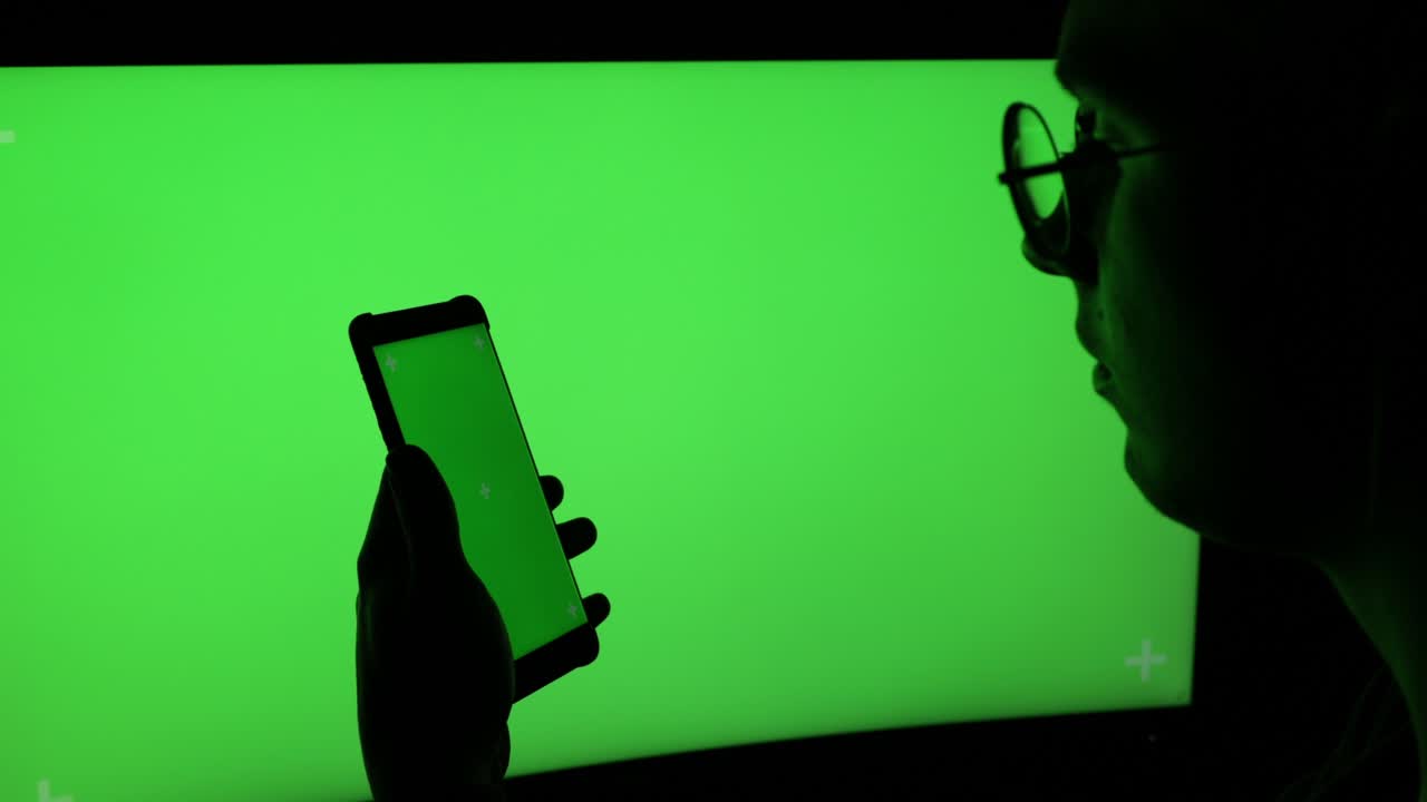 컴퓨터 화면 (녹색 화면) 에 대한 스마트폰을 가진 남자
