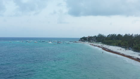 Drone-approaching-moored-wooden-boats-on-the-shoreline-of-Caribbean-Sea-at-Playa-del-Carmen,-Mexico