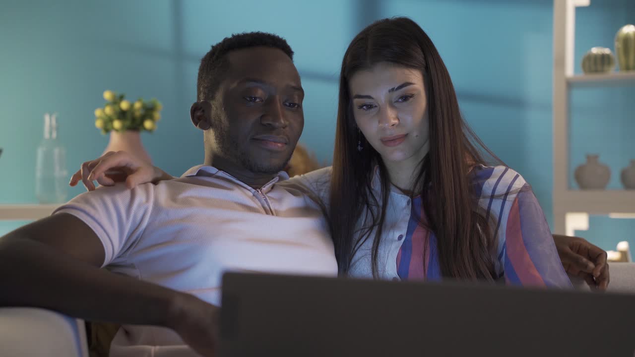 una feliz pareja casada viendo una película en su casa por la noche.