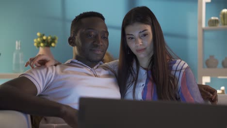una feliz pareja casada viendo una película en su casa por la noche.