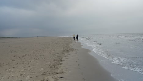 Dos-Amigas-Caminando-Por-La-Orilla-Del-Mar-Del-Norte-Durante-Un-Día-Nublado-En-La-Isla-Texel