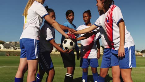 female soccer team clasping hands together on soccer field. 4k