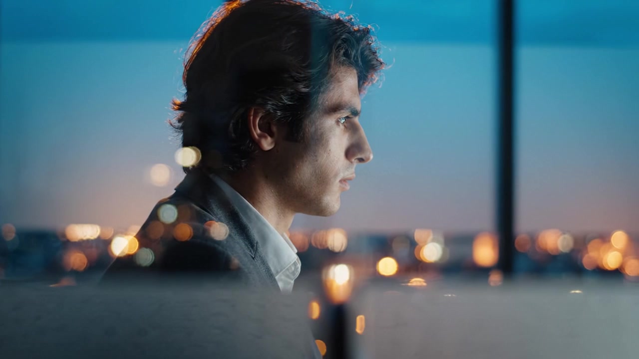 A Thoughtful Individual Gazing Out at a Distant Cityscape, Contemplating Life, Ambitions, and Future Opportunities as the Day Transitions into Night.