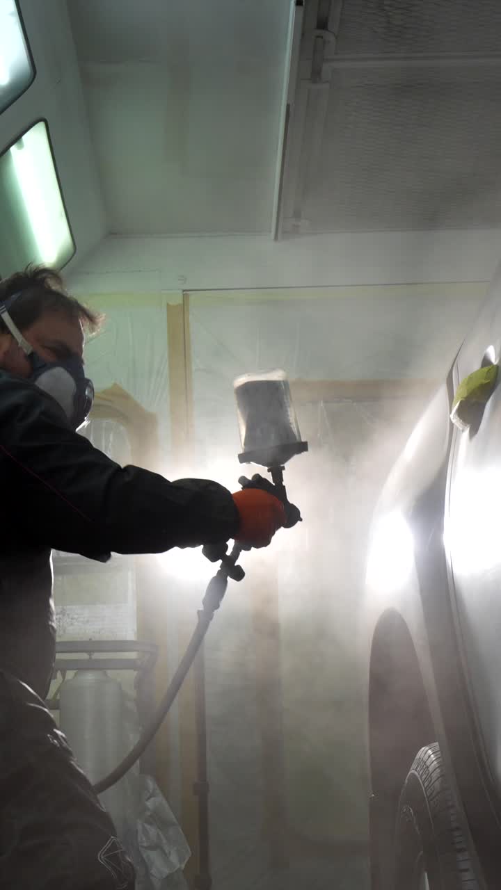 Man in Respirator Mask Spray Painting Car in Auto Body Shop
