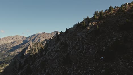 Aerial-parallax-revealing-rocky-mountains-behind-a-rocky-hill-during-the-day