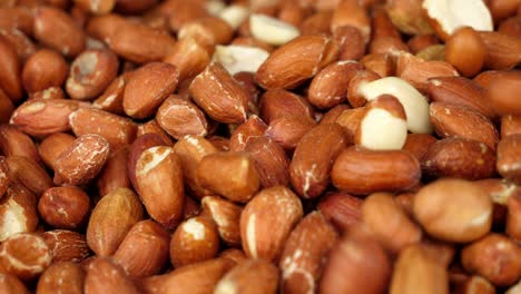 close up on a pile of raw peanuts with more being added to the batch