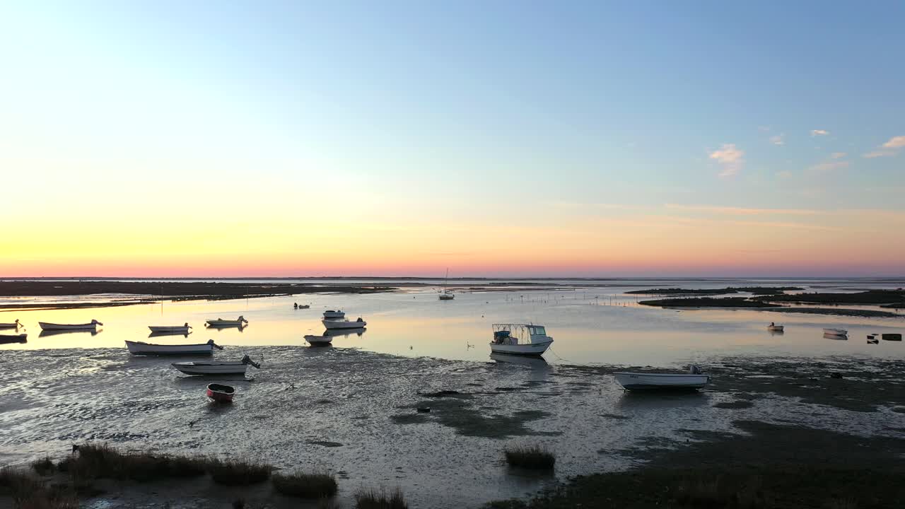 Amazing Orange and Blue Sunset through trees and over incredible Fuseta Olhão reflective ocean with sail boats Portugal, Drone Aerial