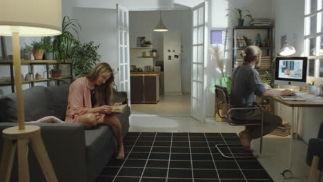 man working on computer while wife reading book