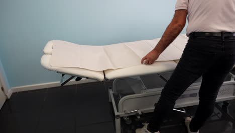 physiotherapist preparing the stretcher for a rehab session inside a clinic