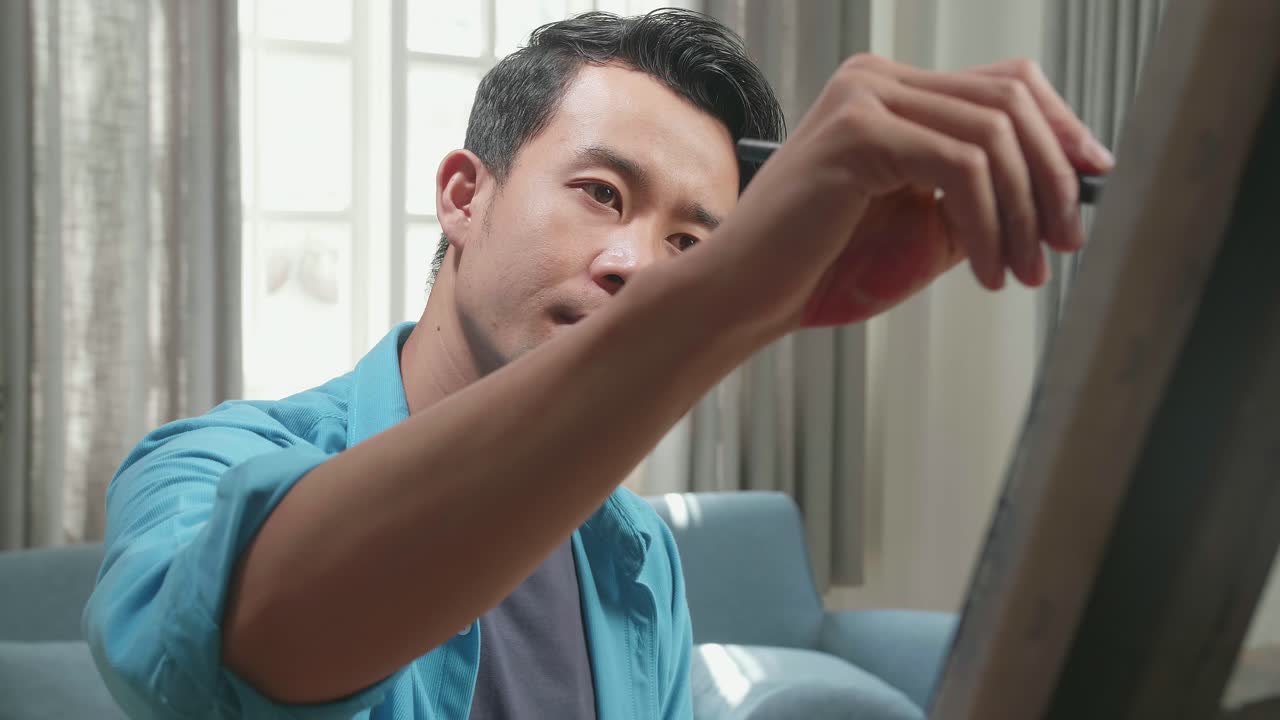 Medium Close Up Of An Asian Artist Man Holding Paintbrush Mixed Colour And Thinking Before Painting On The Canvas