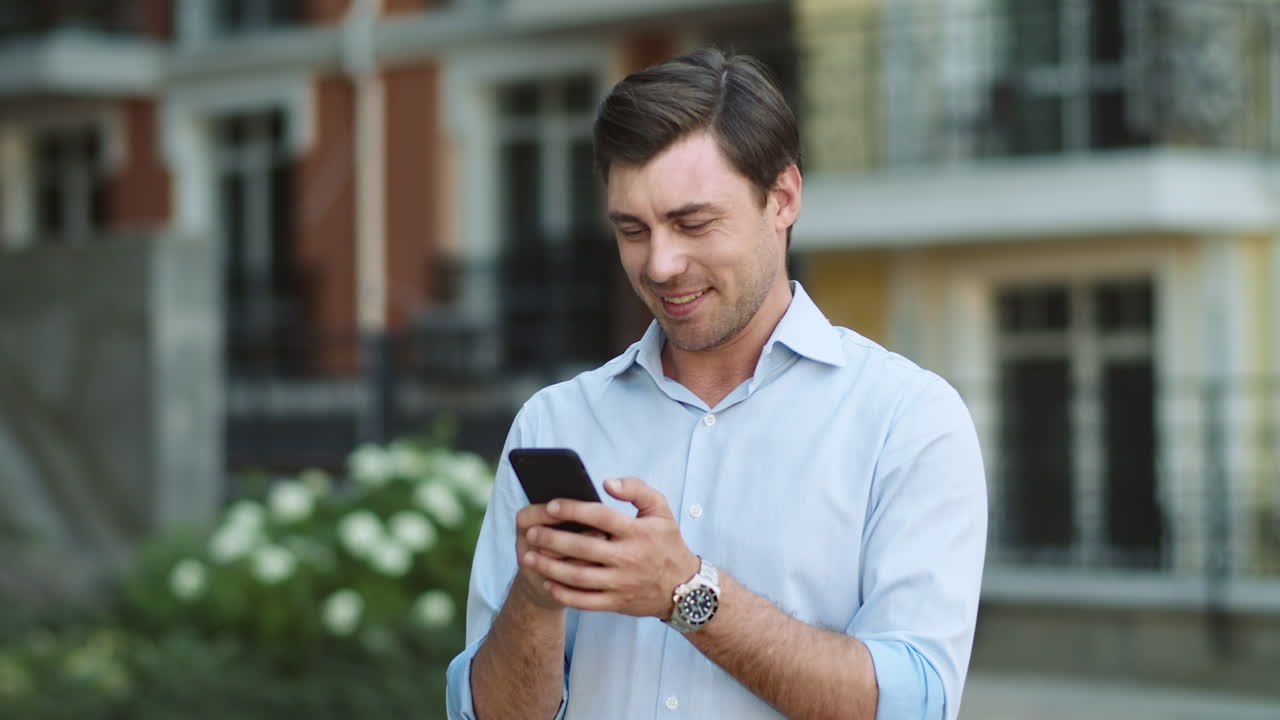 hombre feliz escribiendo en el teléfono al aire libre
