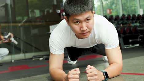 a man performs a plank exercise in a well-equipped gym, showcasing strength and concentration
