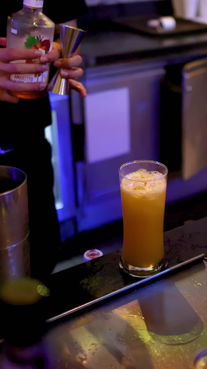 Un barista prepara un cocktail con misurino e alcolici, illuminazione vibrante del bar, ripresa ravvicinata con telecamera a mano.