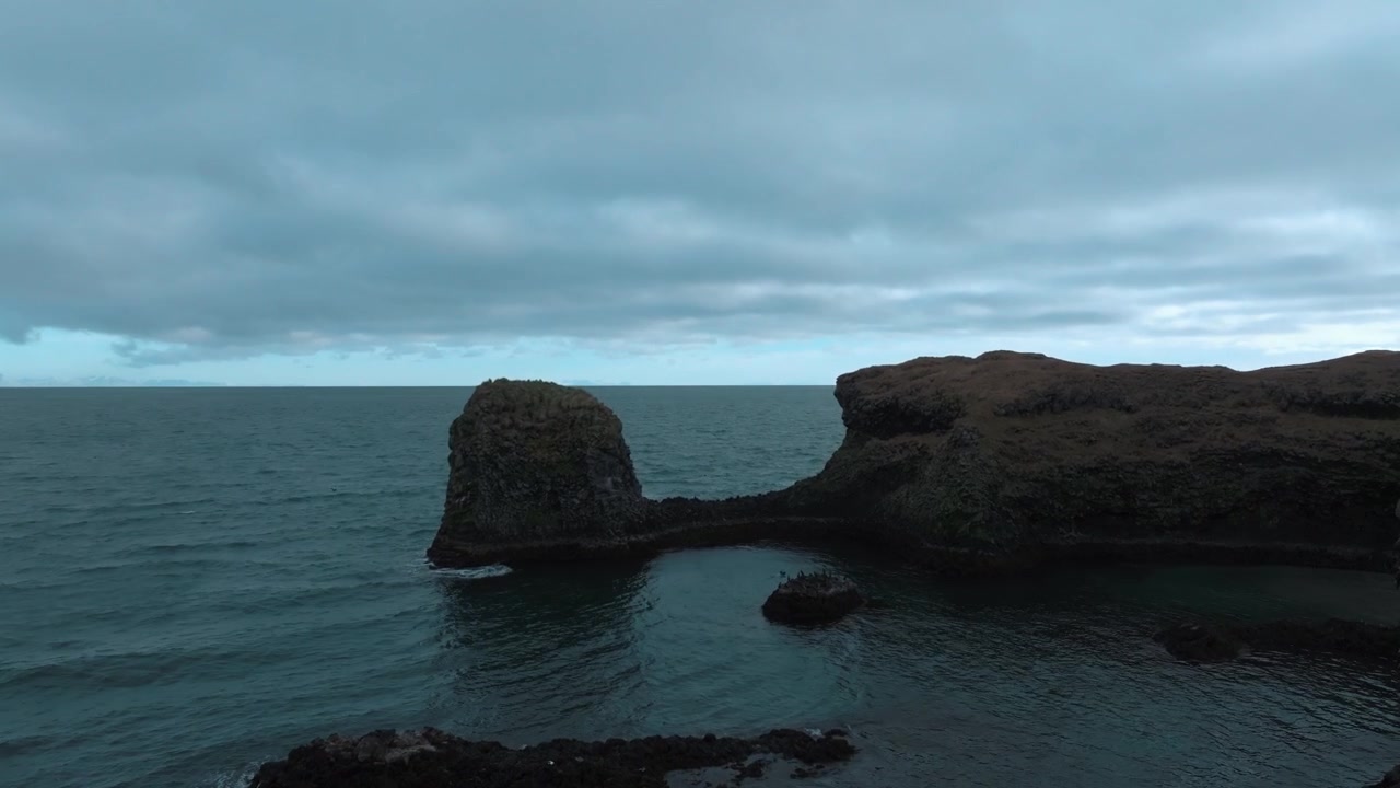 Falésias de basalto de lava negra ao longo da costa da Islândia - sobrevoo aéreo com aves costeiras nas rochas em um dia nublado e chuvoso.