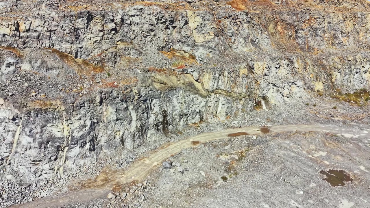 Granite quarry with rocky terrain and a dirt road in the foreground during daylight