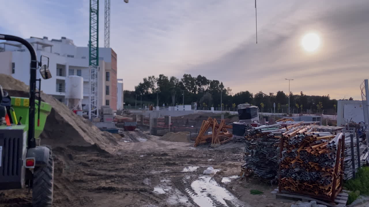 Bau neuer Häuser und Infrastruktur, mit laufenden Bauarbeiten, schwerem Gerät und Baumaterialien bei Sonnenaufgang.