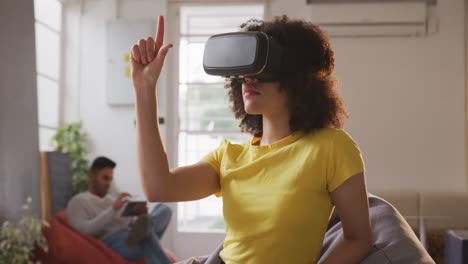 mixed race woman wearing vr headset in creative office