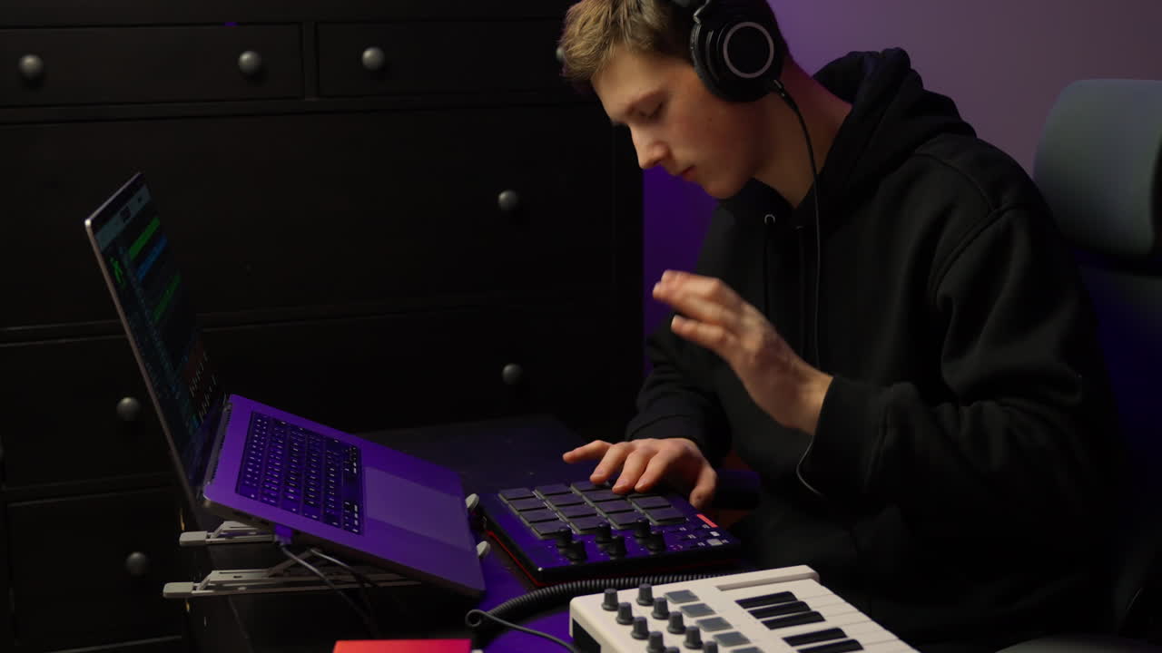 Male musician adjusts synthesizer controls shaping tones in home studio with calm introspective energy