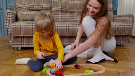 madre con una hija pequeña niña montando un tren de juguete en bloques de ferrocarril de madera juego de mesa en casa