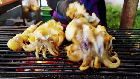 Street-food-seller-is-fresh-grilled-squid-barbecued-meat-skewers-with-sauce