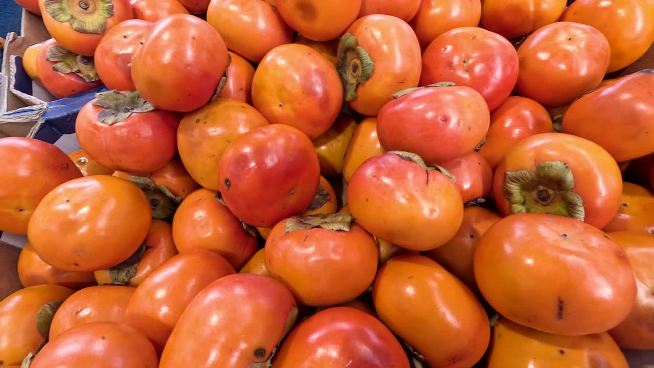 Bright persimmons arranged in a market setting, showcasing their vivid orange hues under natural lighting