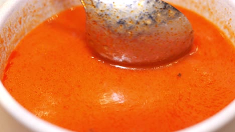 close-up of a bowl of red soup with a spoon