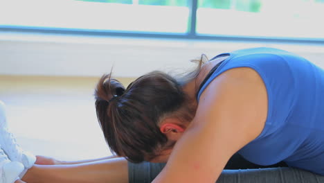 video de una mujer sentada en una postura de yoga inclinada hacia adelante