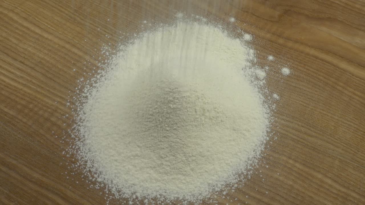 Mengayak tepung di atas papan. Pengambilan gambar di dapur