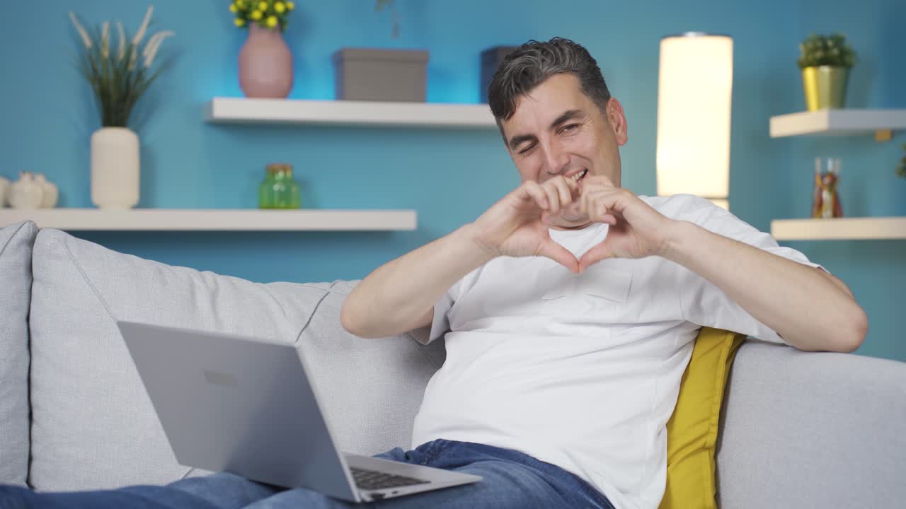 편안한 표정을 가진 남자가 카메라에 심장을 만들고 있습니다.