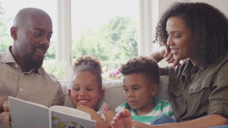 Cerca-De-Padres-Sentados-En-El-Sofá-Con-Niños-En-Casa-Leyendo-Un-Libro-Juntos