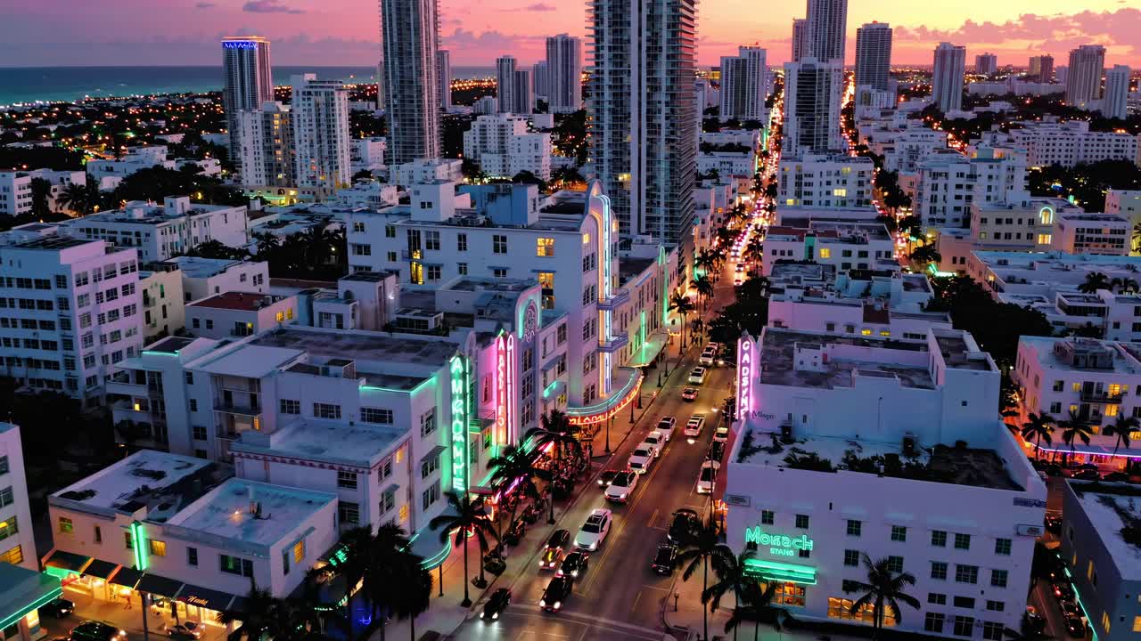 Aerial video of a vibrant cityscape at sunset, showcasing neon-lit streets and modern skyscrapers