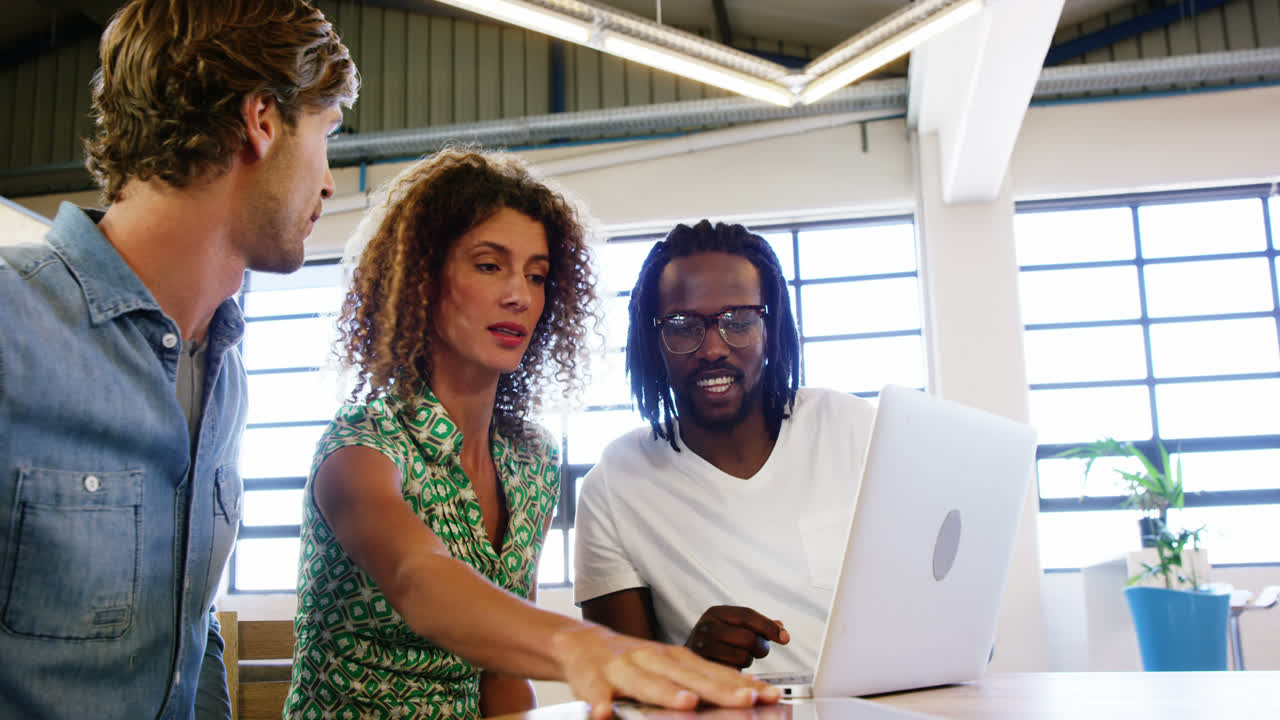 Colleagues discussing with each other over laptop