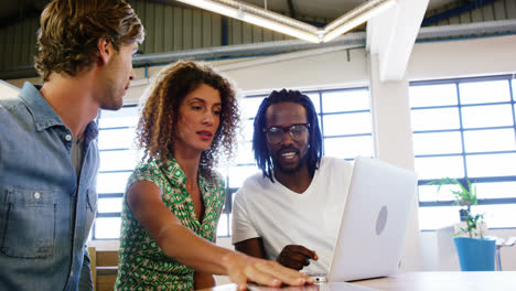 colleagues discussing with each other over laptop