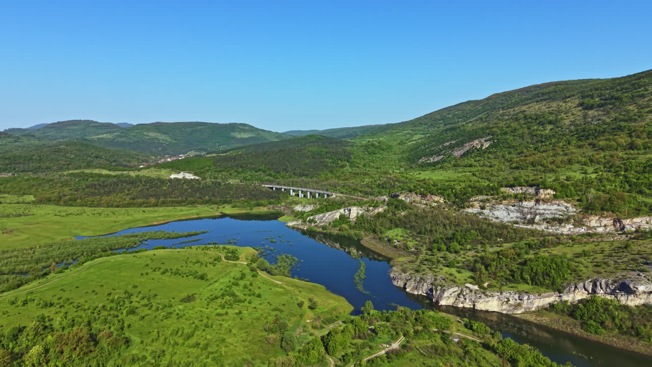 Green landscape with river and bridge in a mountainous area under a clear sky during daytime