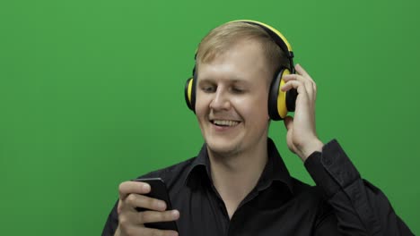 guy listens to music in wireless yellow headphones and dances. chroma key